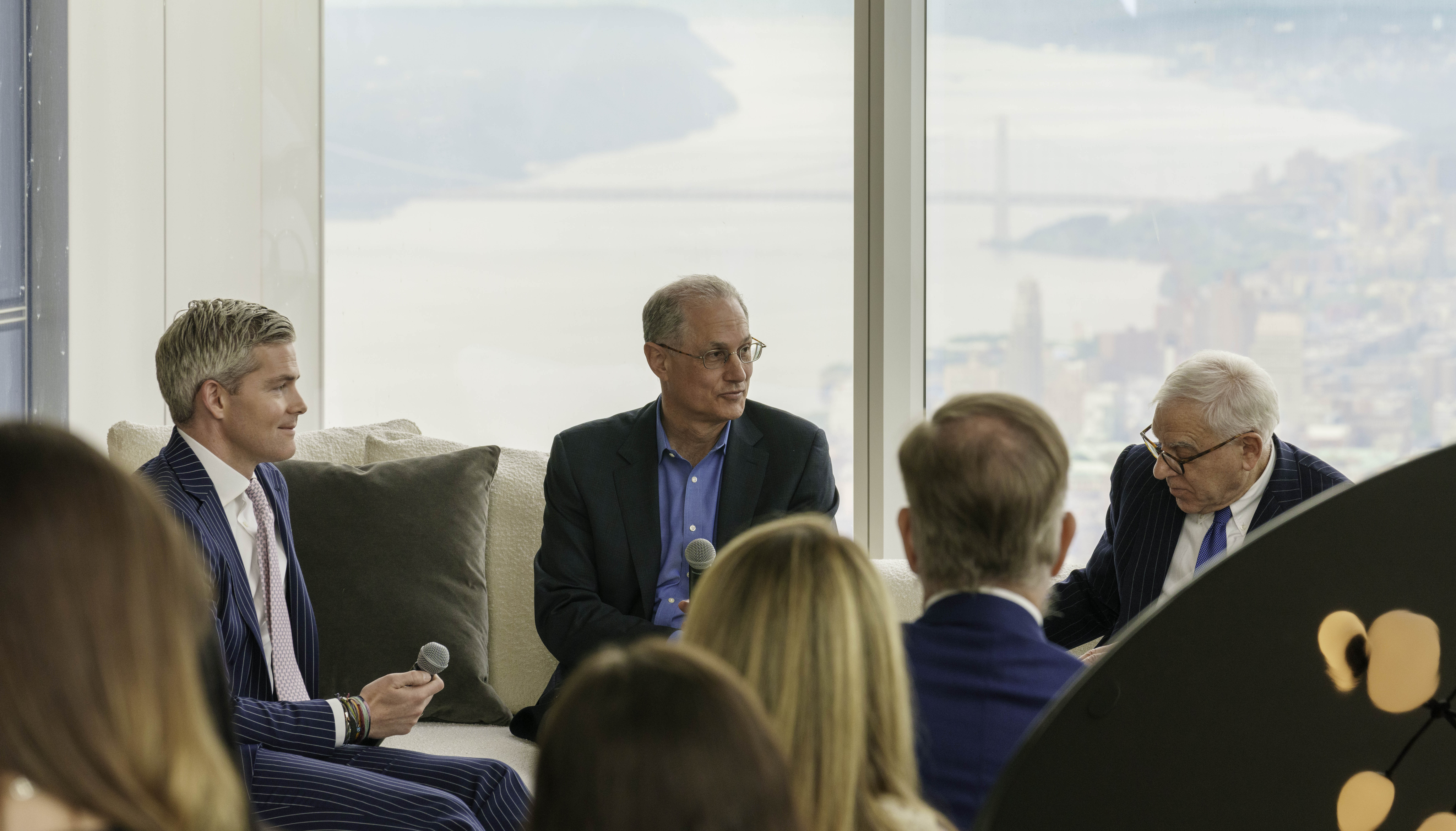 Ryan Serhant, David Golub, and David Rubenstein in panel discussion on real estate and the stock market overlooking New York